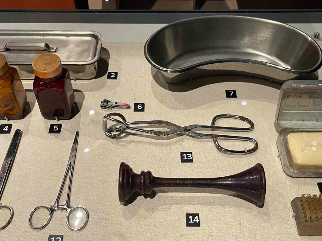 |產婆的助產器材:4.綁臍帶用線、5.紅藥水、6.嬰兒用指甲剪、7.彎盆、12.止血鉗、13.產鉗、14.單耳式聽診器